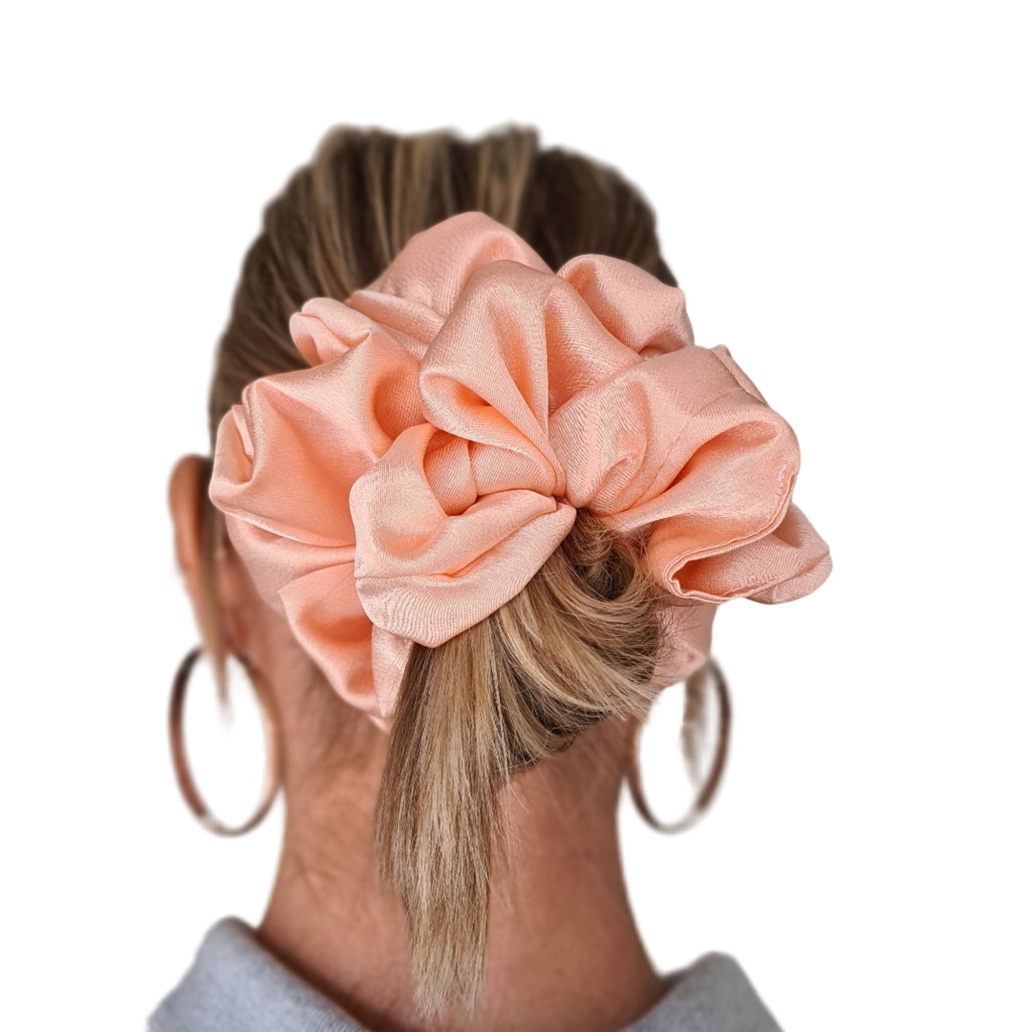 Person wearing a large peach scrunchie in their hair against a neutral background